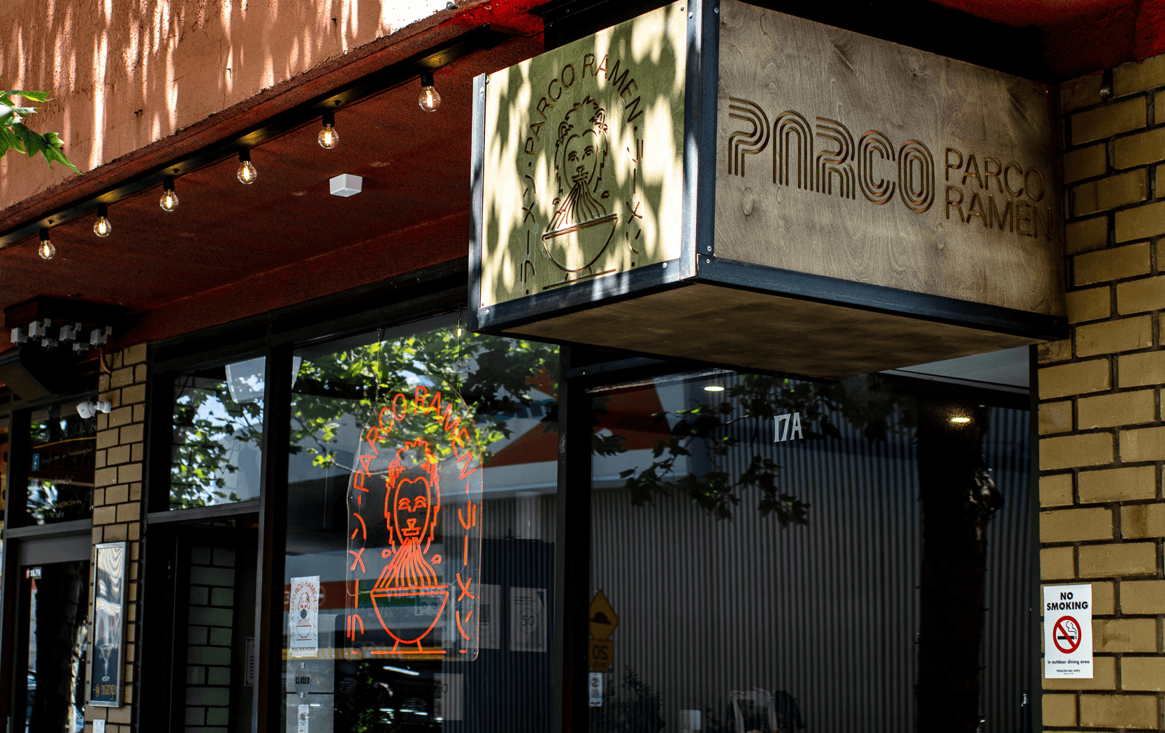A storefront with a red neon sign in the window and a sign hanging above the door.